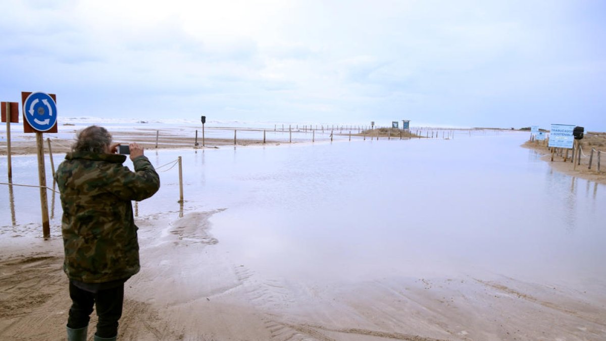 Un home pren imatges de l'accés a la barra del Trabucador inundat pel mar.