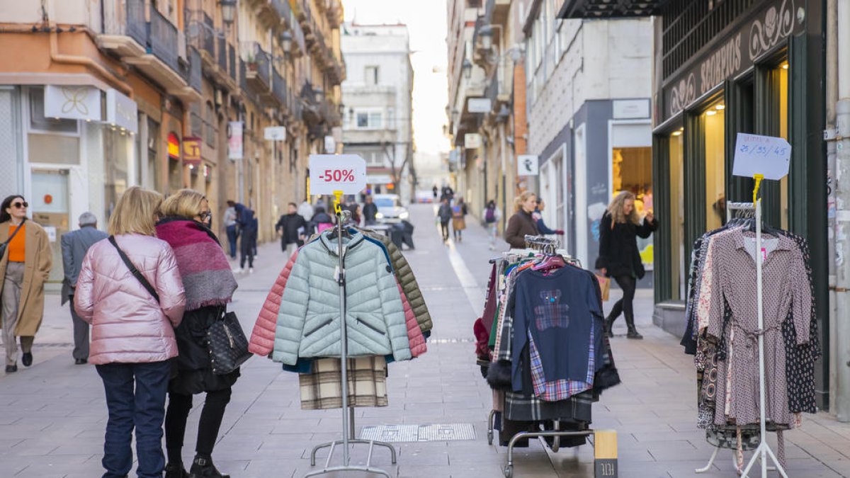 Gent mirant els productes de les paradetes de les botigues del Carrer Sant Agustí.