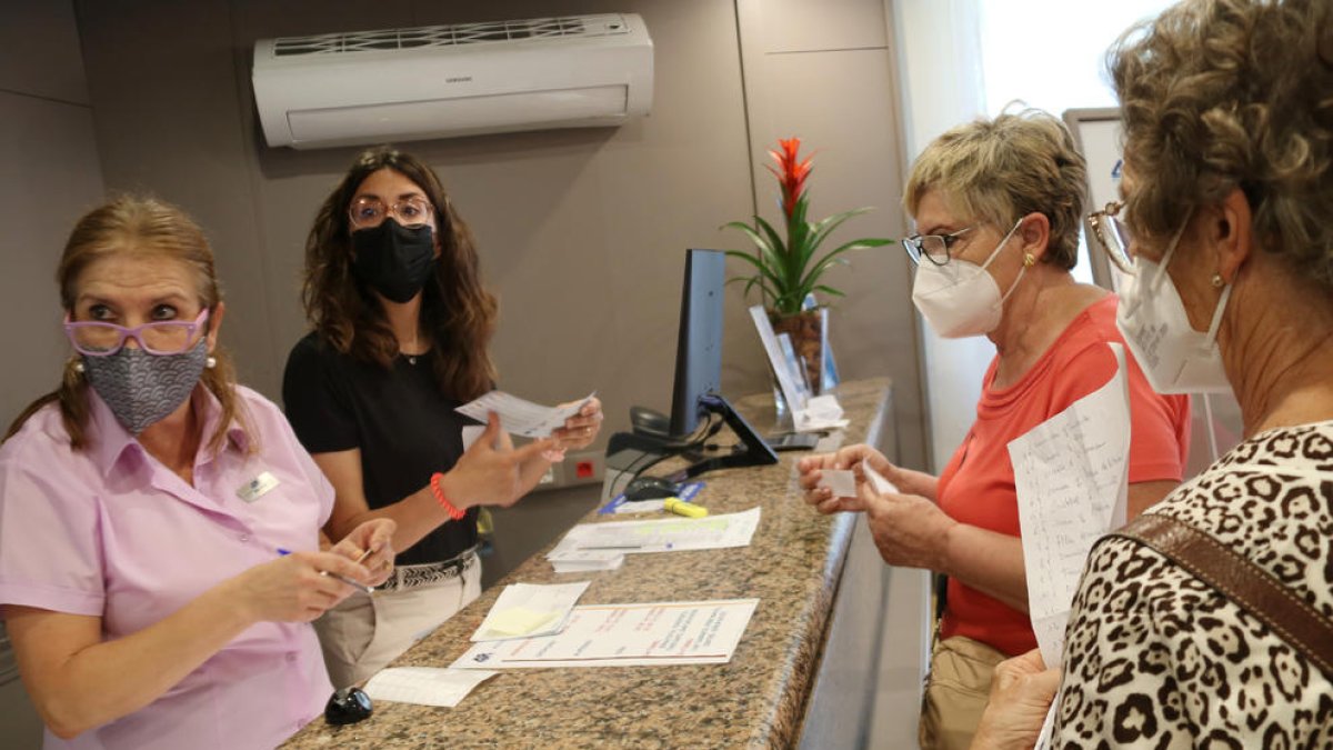 Dues treballadores a la recepció d'un hotel de Salou, atenent clientela.