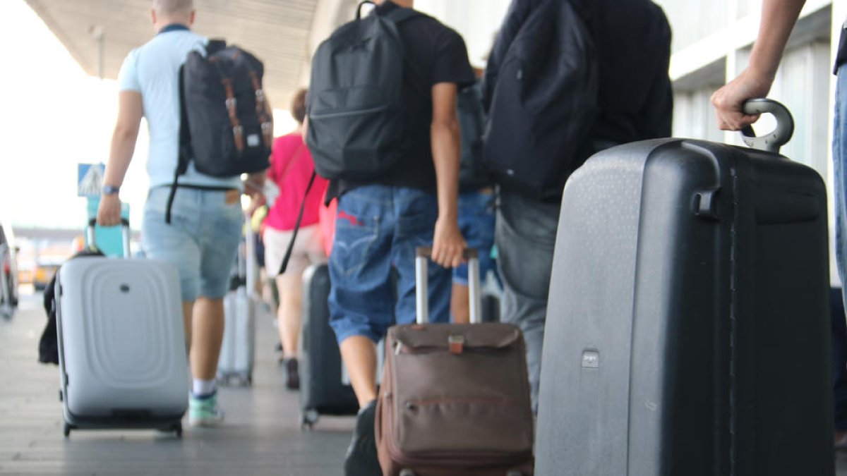 Turistes amb maletes a la sortida de l'aeroport del Prat.