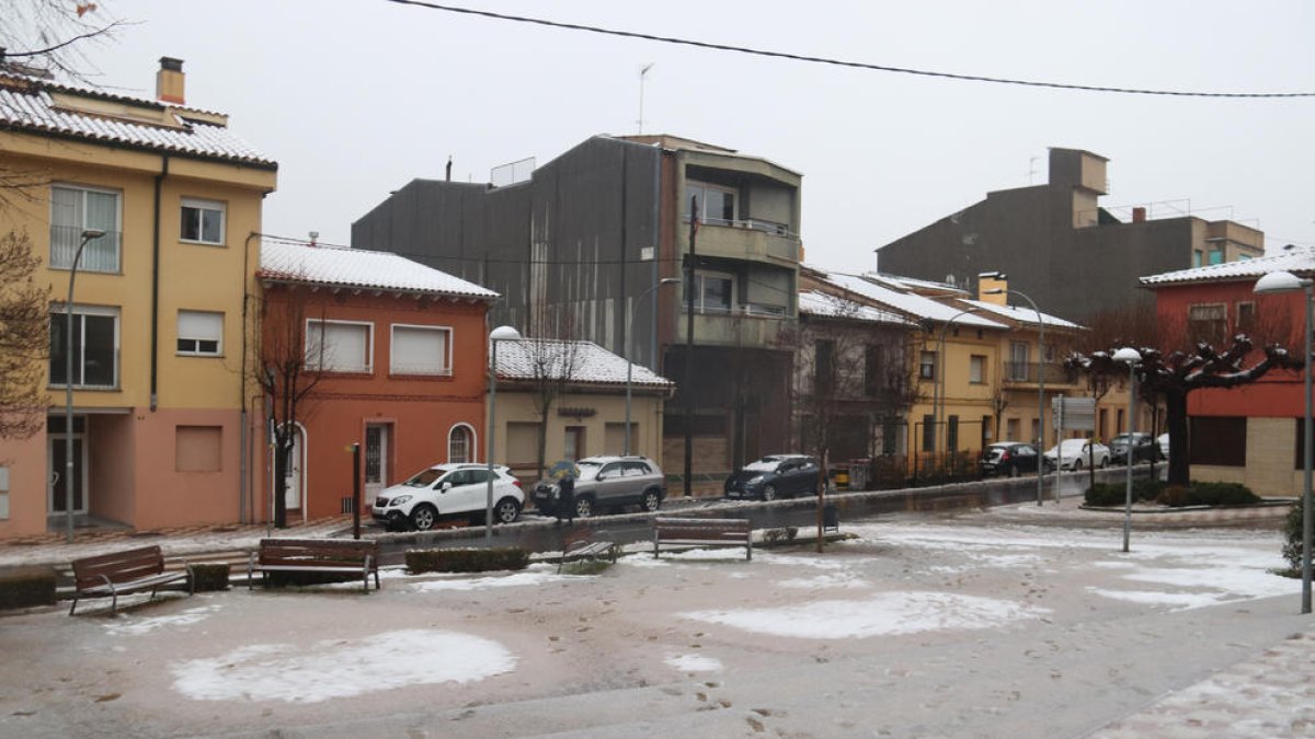 Diverses cases de Sant Hilari Sacalm enfarinades i una plaça amb la neu mig fosa per la pluja.