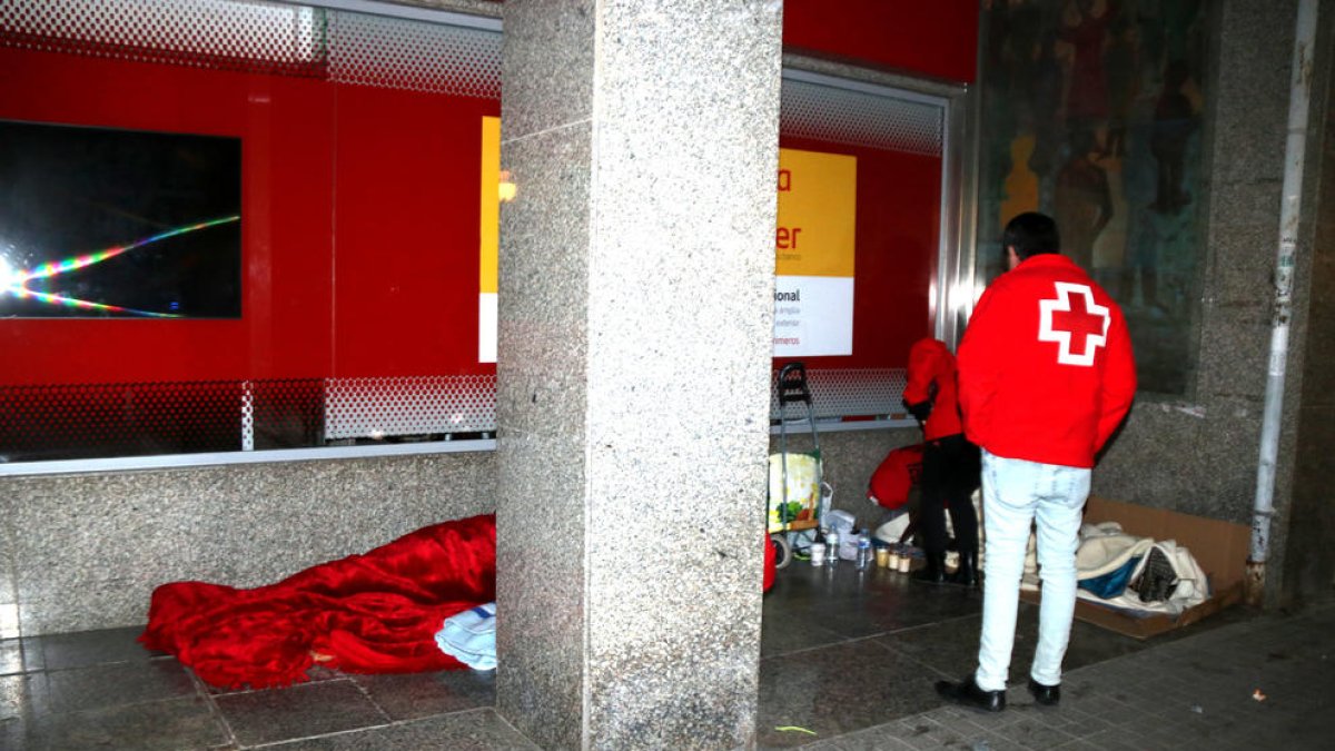 Voluntarios de Cruz Roja ofreciendo mantas y bebidas a los sin techos durante la Operación Iglú.