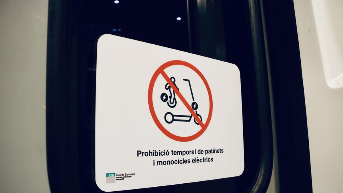 Cartell anunciant la prohibició temporal d'entrar amb patinets i motocicletes eléctriques al transport públic.