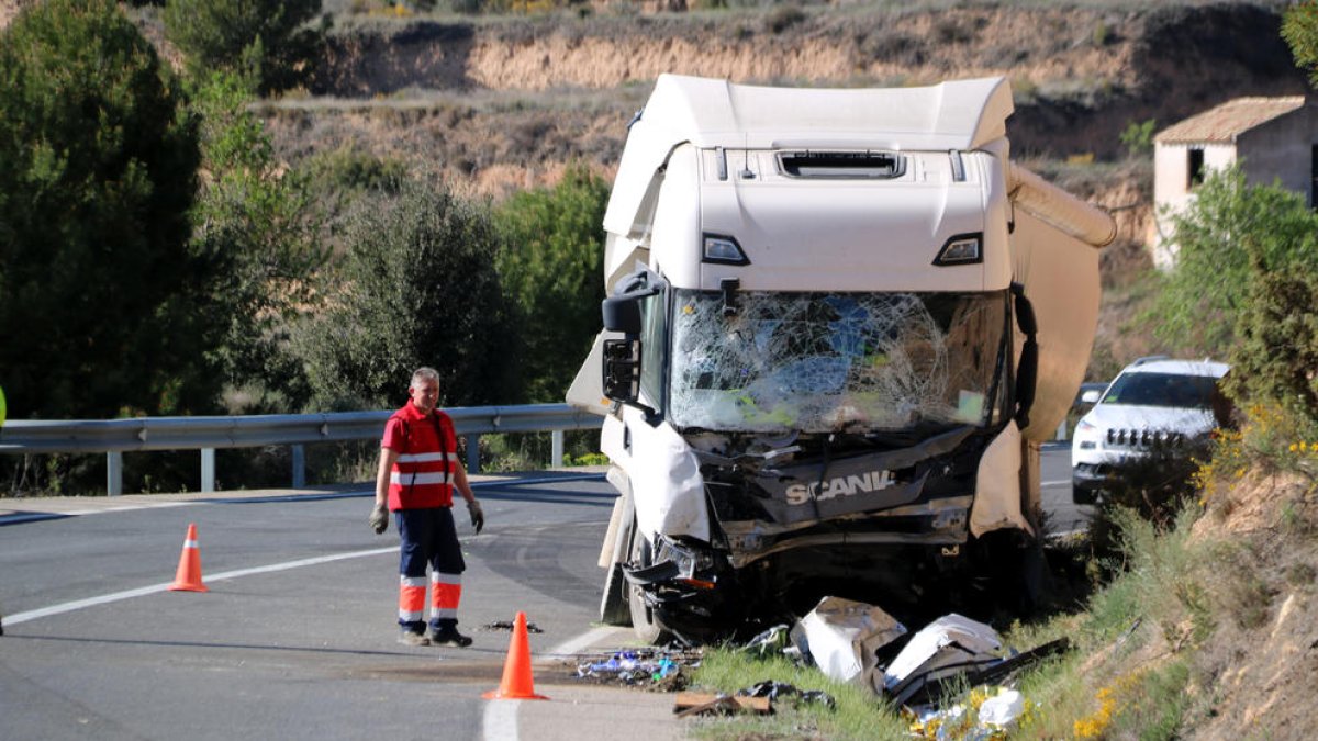 Un operari retira les restes del vehicle que han quedat davant del camió accidentat a Batea.