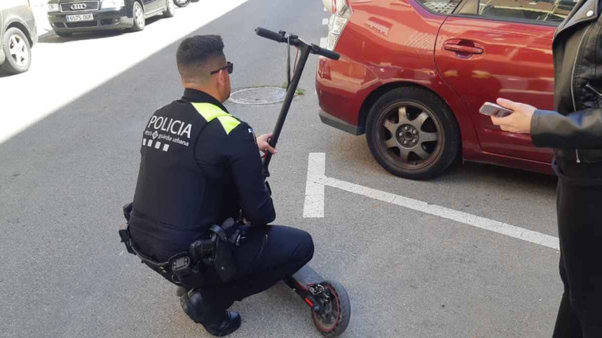 Un agente de la Guardia Urbana de Reus examina un patinete eléctrico.