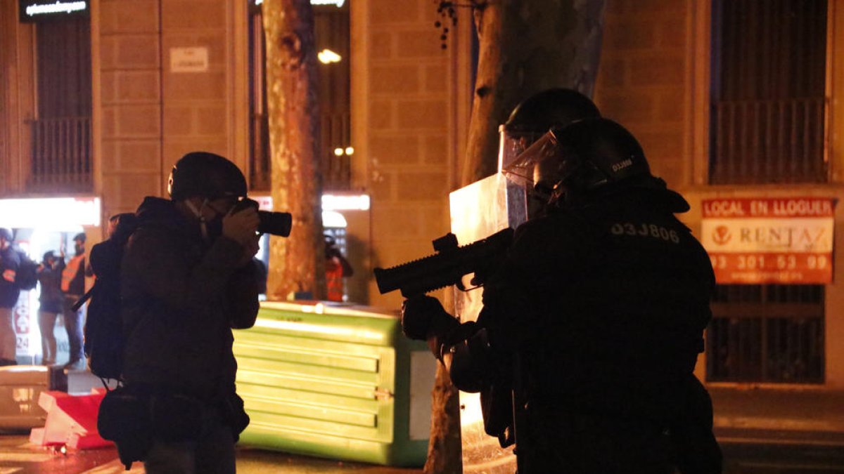 Un periodista fotografía a un agentes de los Mossos con una lanzadera foam.