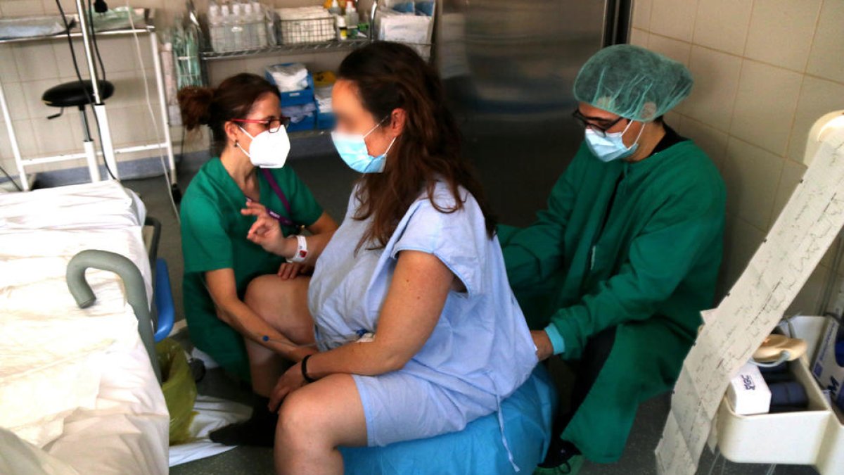 Una matrona comprobando la situación de una mujer embarazada, minutos previos a dar a luz.