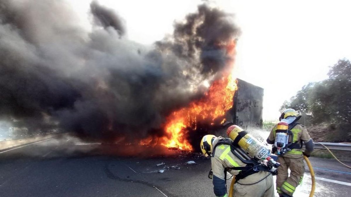 Dos bombers treballen en l'extinció d'un camió incendiat a l'AP-7, a Vilafranca del Penedès.