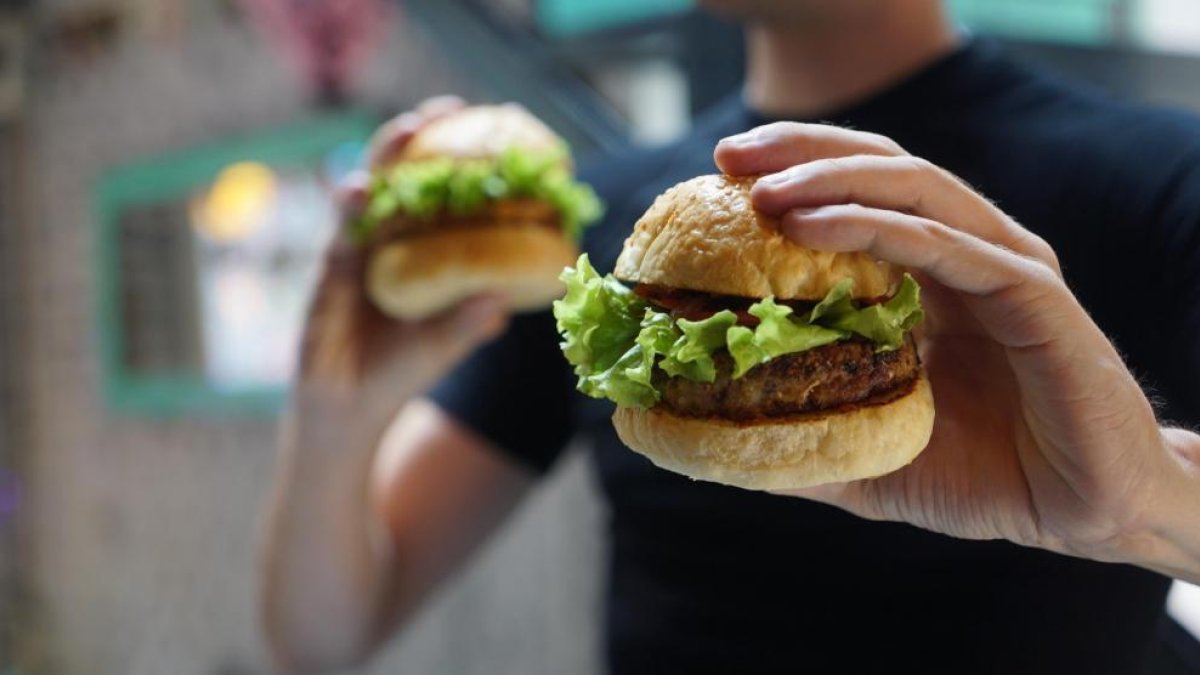 Un home sosté dos hamburgueses de carn.