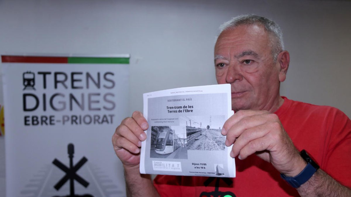 El portaveu de Trens Dignes, Josep Casadó, mostra un cartell de l'acte de presentació del projecte de tren-tram de les Terres de l'Ebre.