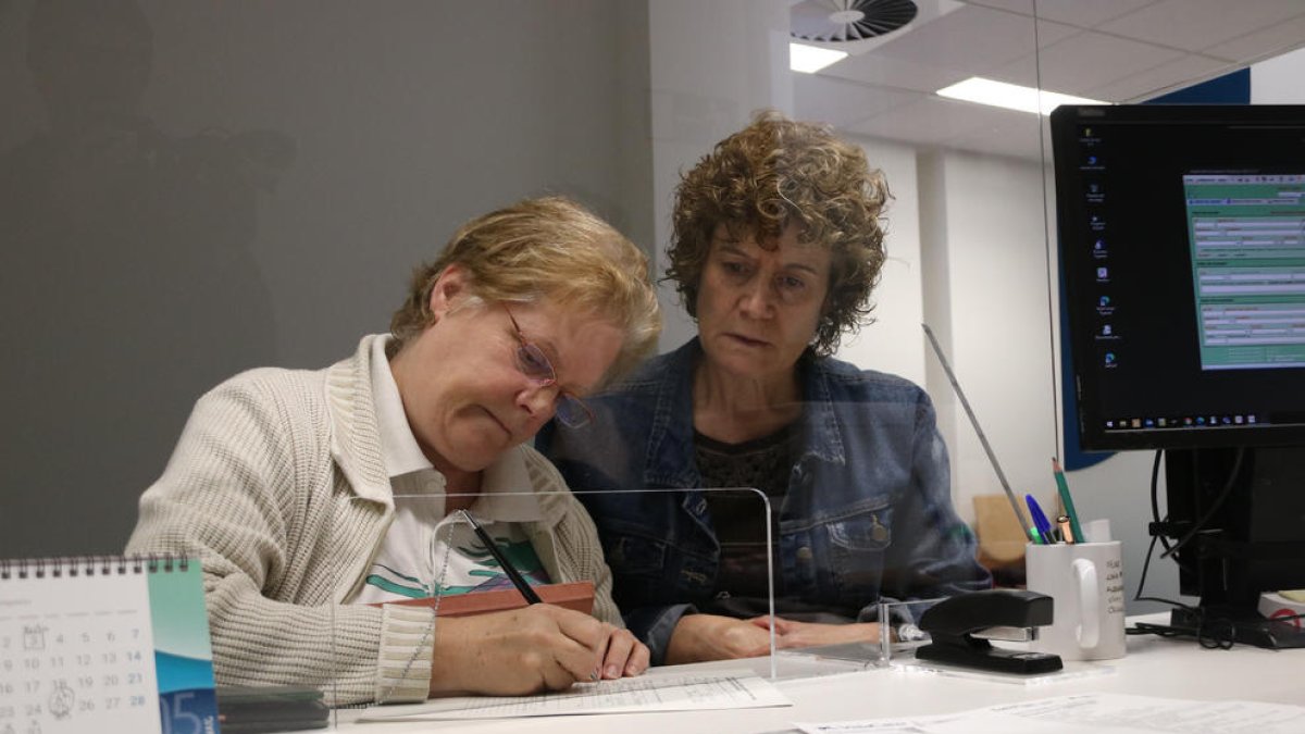 Dues usuàries fent un tràmit a l'oficina de l'Agència Tributària de Catalunya a Figueres.