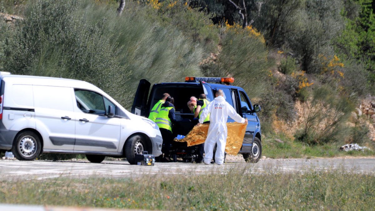 Els agents de la policia i els serveis funeraris aixecant el cadàver de la víctima.