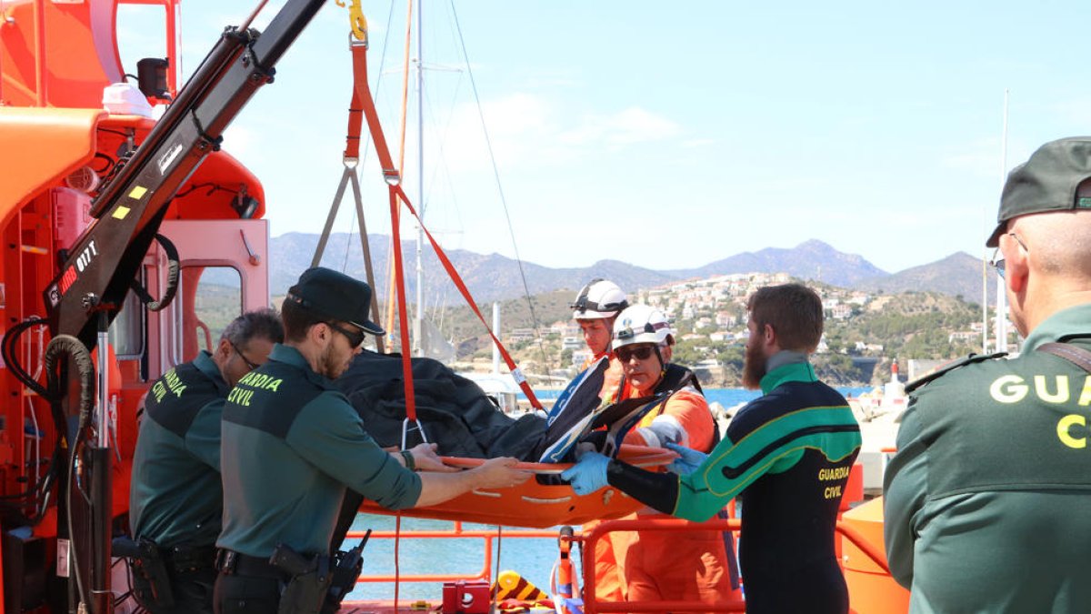 Efectius de la Guàrdia Civil, dels GEAS i de Salvament Marítim baixant el submarinista mort de l'embarcació.