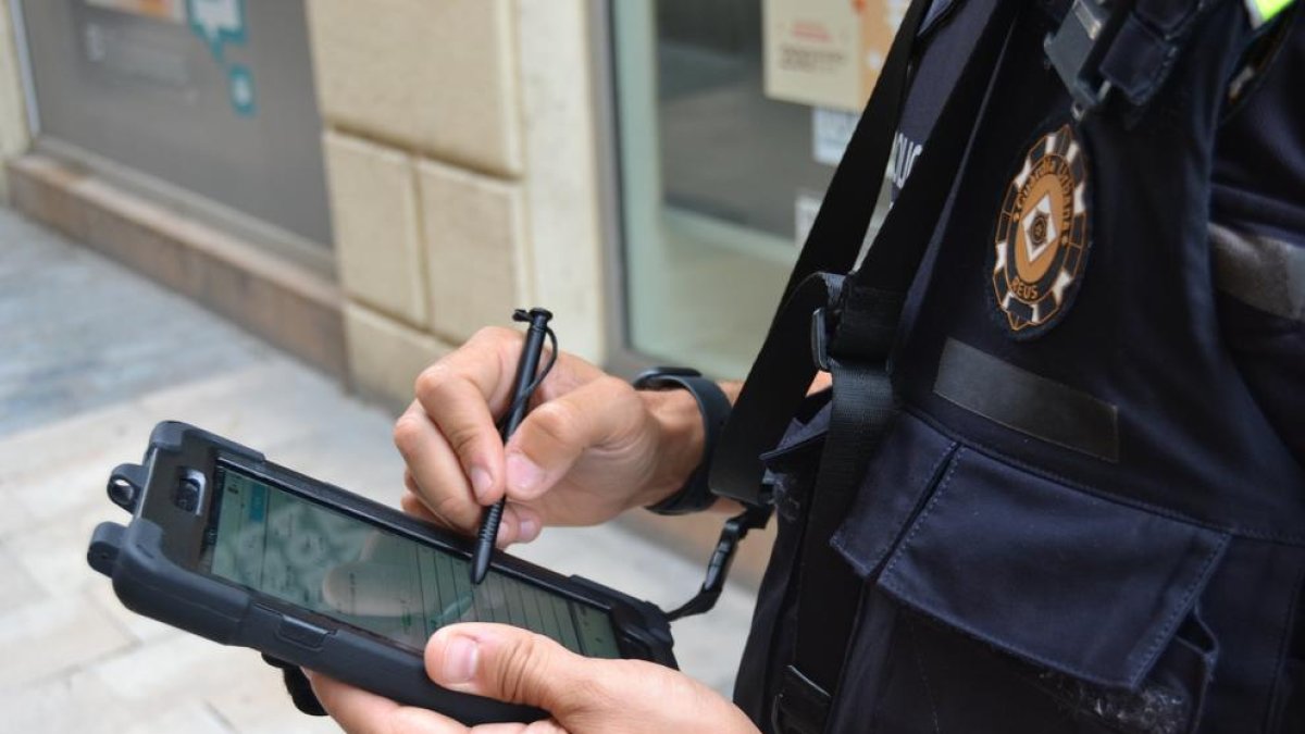 Un agente con una tableta electrónica realizando un trámite a pie de calle.