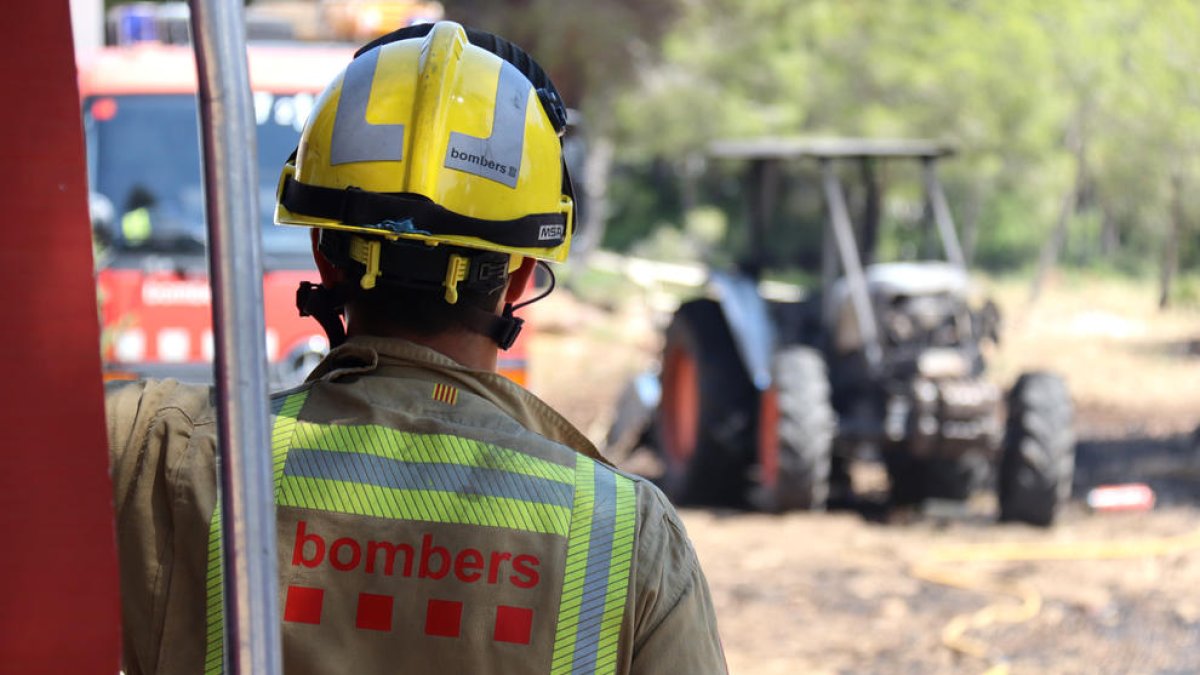Un bomber mirant el tractor calcinat que ha provocat l'incendi a Mont-roig del Camp.