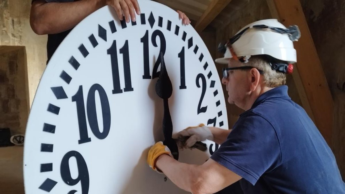 Un operario a punto de colocar el reloj en la fachada del consistorio de Tarragona.