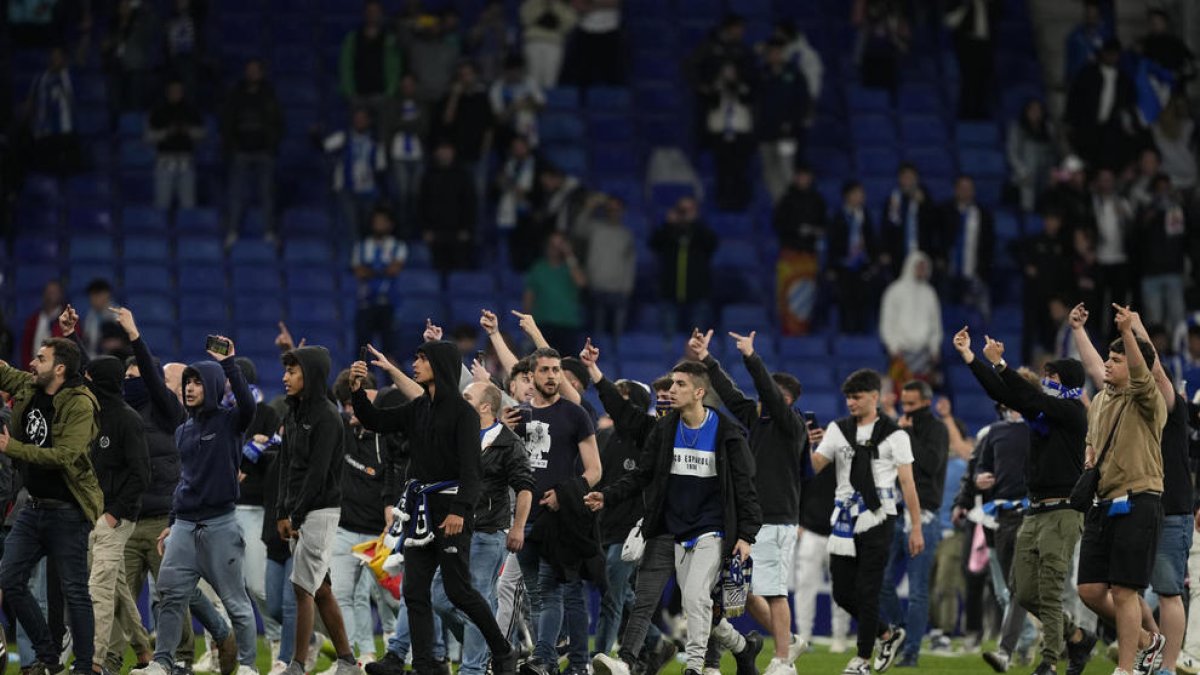 Algunos aficionados redicales del Espanyol invaden el campo tras el partido de contra el FC Barcelona en el RCDE Stadium.