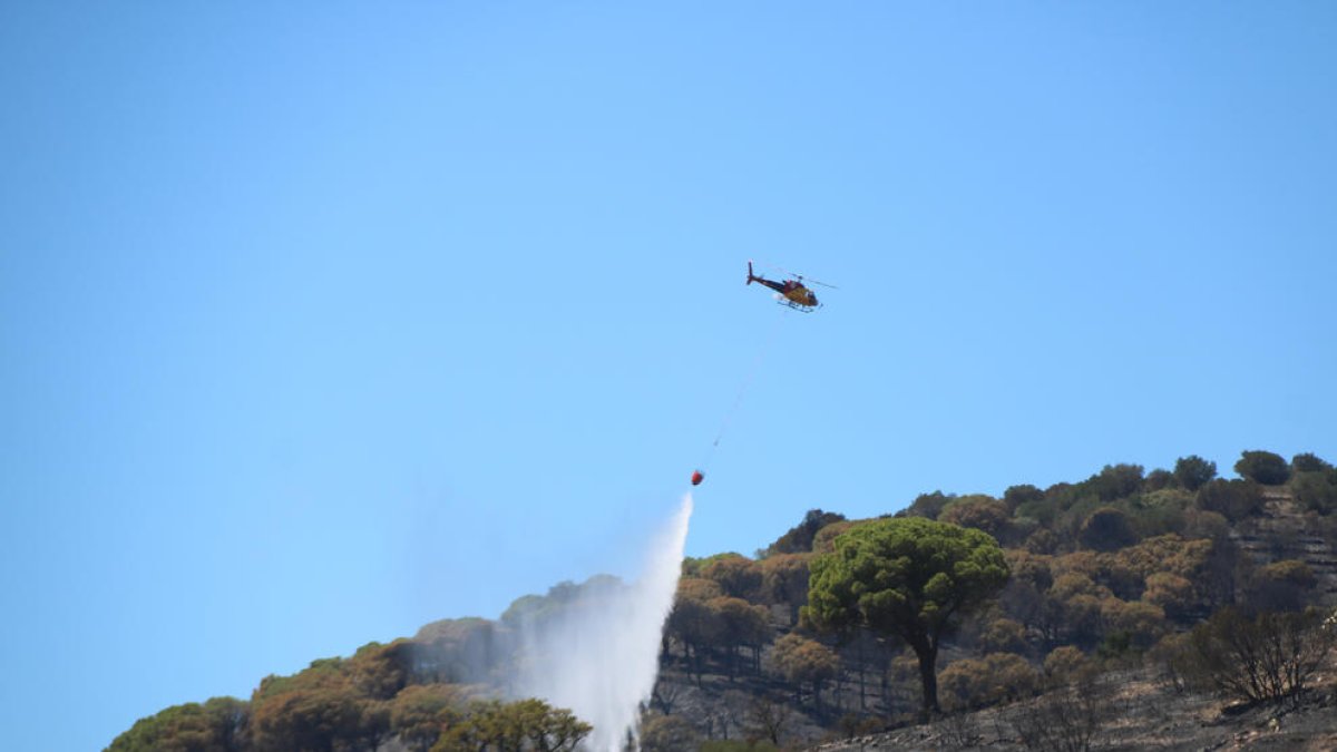 Un helicòpter descarregant en un dels focus de l'incendi de Portbou.