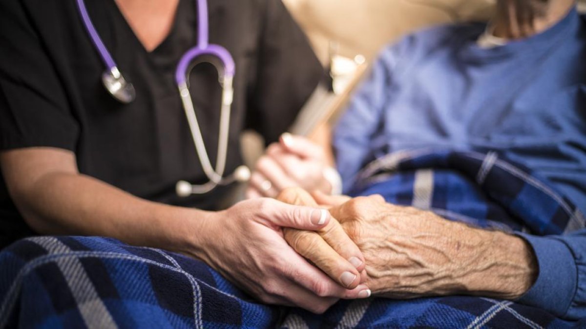 Persona anciana de la mà de la seva cuidadora