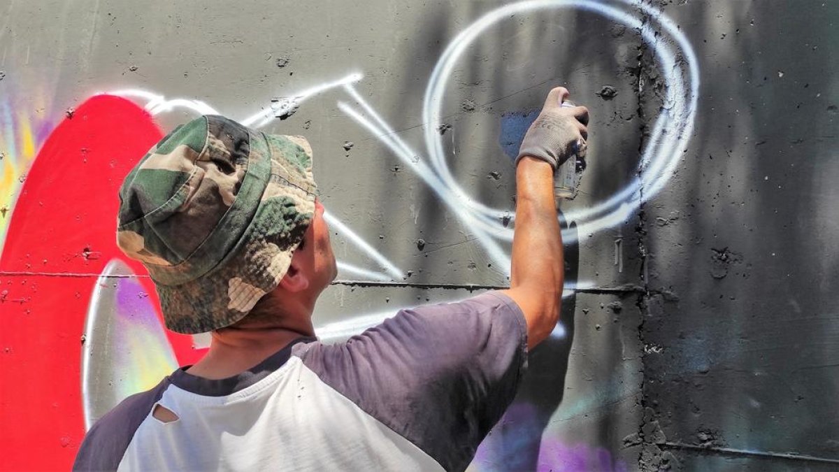 Instant capturat d'un dels artistes pintant un grafiti al mur durant la jornada de dissabte.