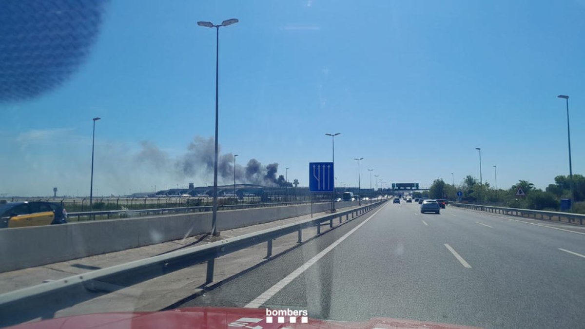 Columna de fum d'un autobús que ha cremat a la T1 de l'aeroport del Prat.