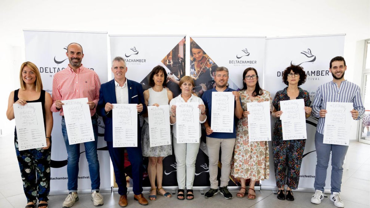 Laura Ruiz i Pau Rodríguez, als extrems de la foto, amb representants dels ajuntaments per on passarà DeltaChamber Music Festival, mostrant el cartell de la vuitena edició.