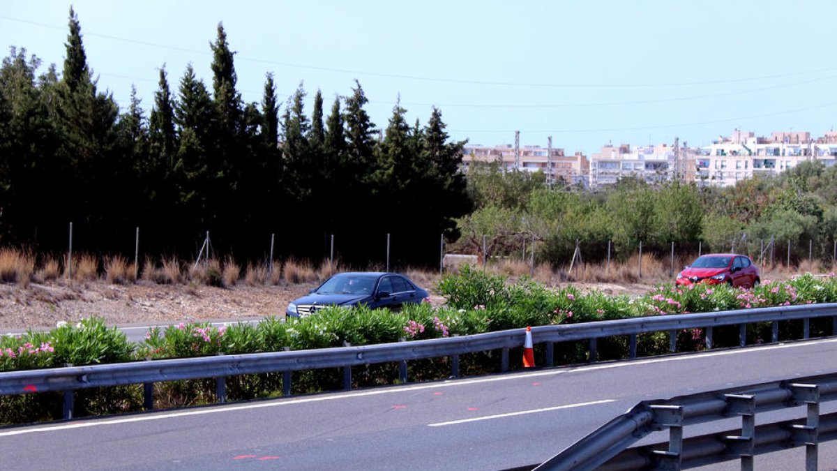 Imatges del tram de l'autopista AP-7 amb marques de la investigació de l'accident per part dels Mossos i el nucli urbà de l'Ametlla de Mar, al fons.