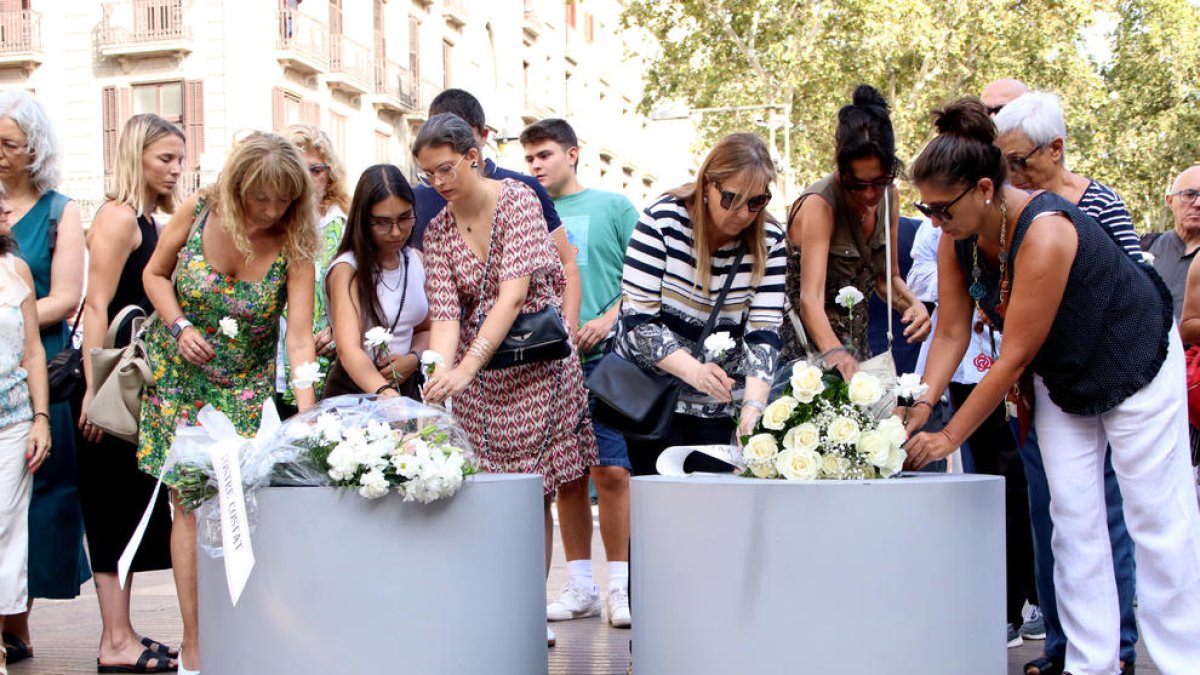 Familiars i víctimes del 17-A dipositen clavells a les jardineres de la Rambla.