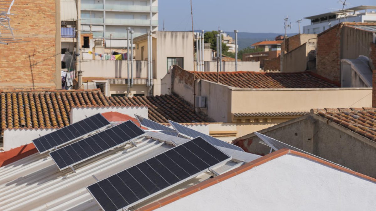 Imatge de plaques solars fotovoltaiques instal·lades a la teulada d'un immoble.