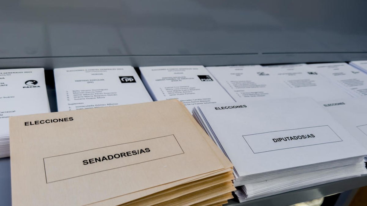 Paperetes, sobres, taules i aigua, disposats en un col·legi electoral.