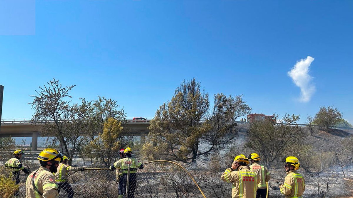 Els Bombers treballen en un incendi de vegetació al voral de l'AP-2 al Pla de Santa Maria.