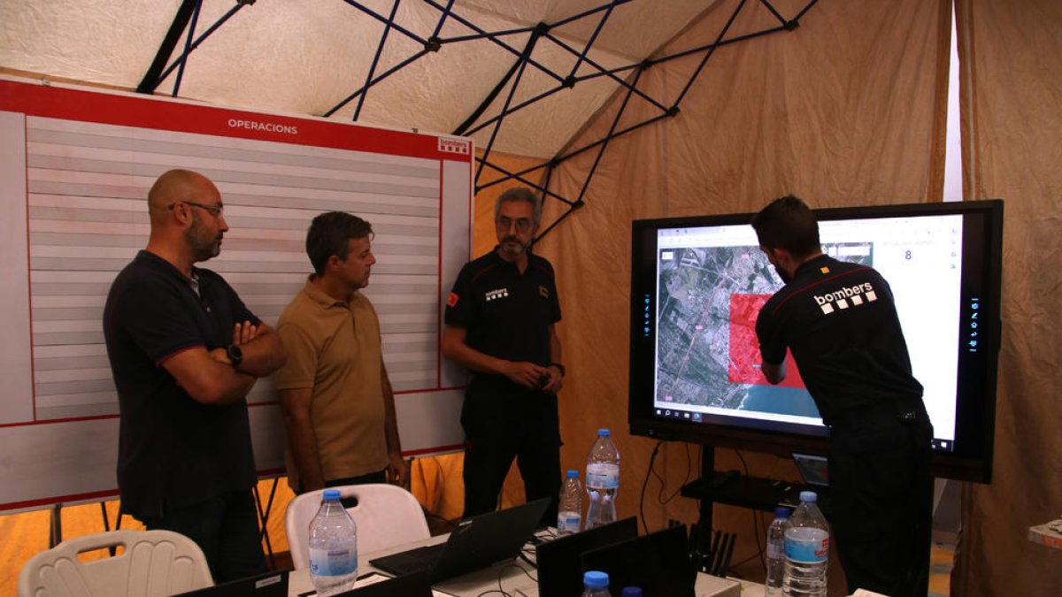 El inspector del cuerpo de Bomberos, Oriol Corbella, mostrando a las autoridades locales la zona afectada por las trombas de agua en el centro de mando.