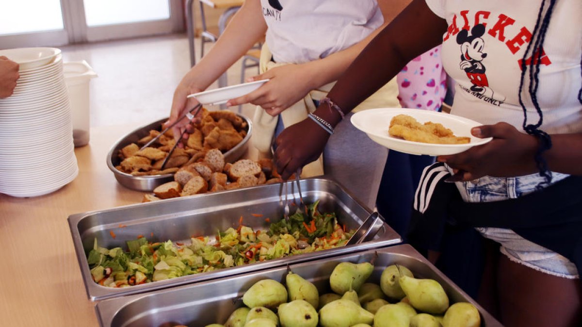 Imatge d'arxiu de dues alumnes servint-se el dinar en un plat.