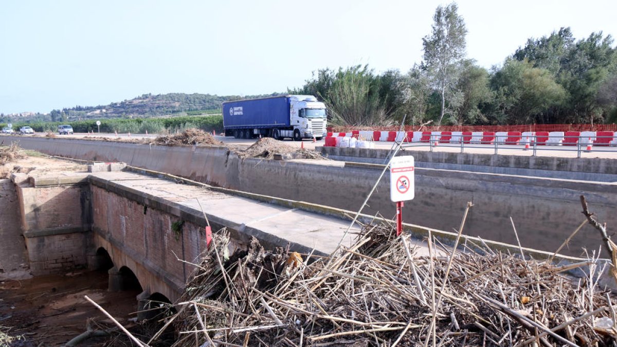 Brossa acumulada al costat del viaducte del canal de la Dreta de l'Ebre sobre el barranc de la Galera i trànsit per la C-12, al fons.