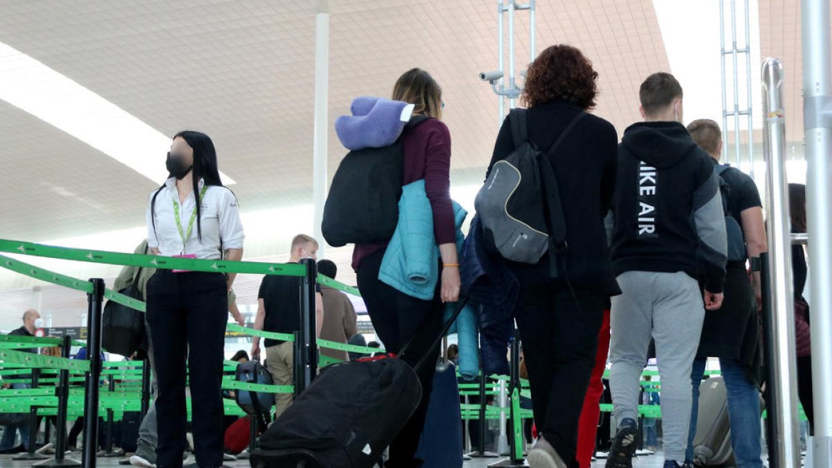 Passatgers a l'aeroport del Prat en direcció a la zona d'embarcament.