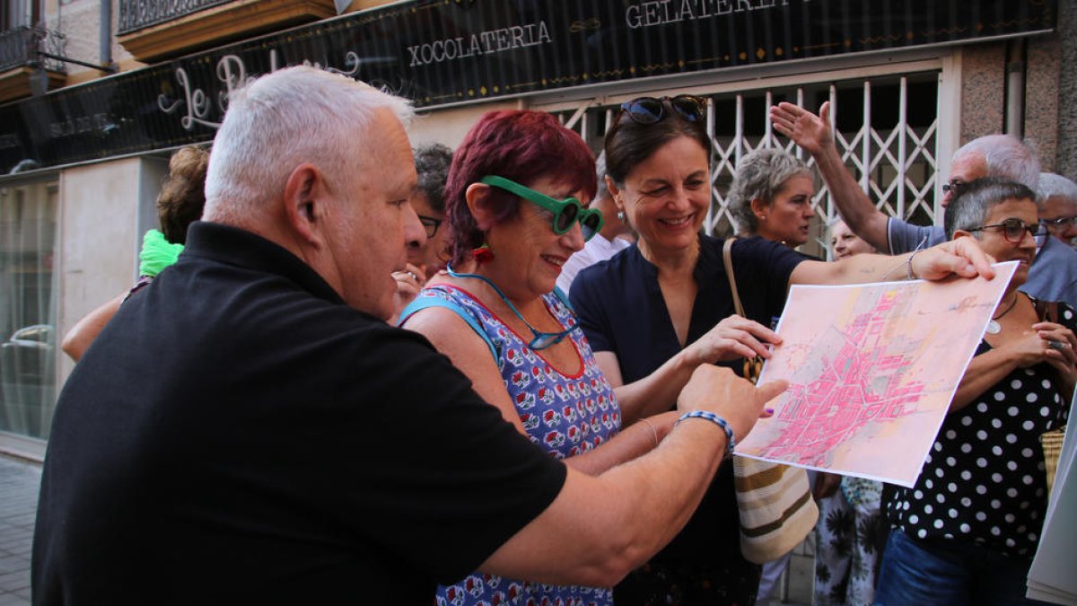 Tres personas mirando un mapa de la ciudad durante la ruta por la calle amplia organizada por l'Associació Espais Ocults en la novena edición de 'Reus Ocult'.
