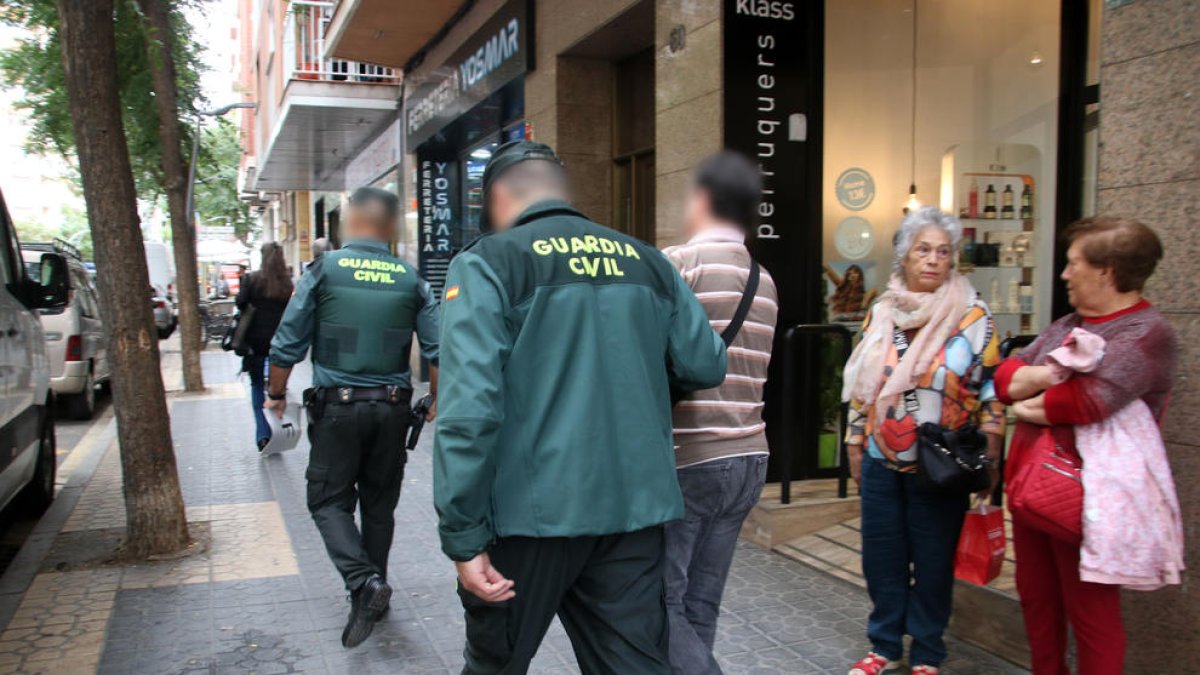 Dos policies de la Guàrdia Civil sortint amb un detingut en un dels registres fets a Tarragonal'operatiu policial conjunt amb els Mossos d'Esquadra.