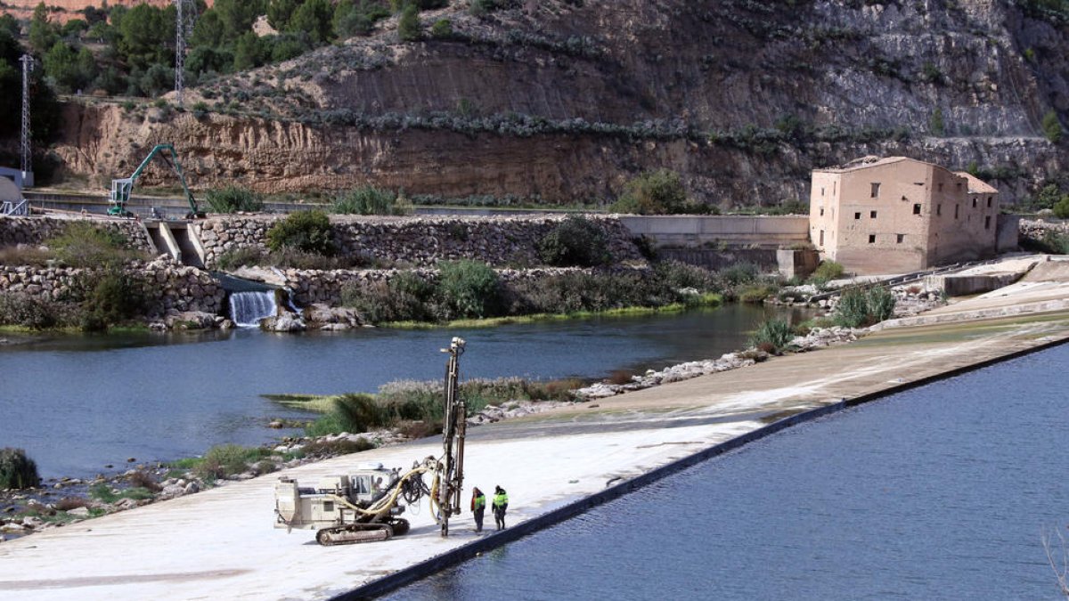 Máquinas y operarios trabajando sobre el azud de Xerta para reparar las rendijas y filtraciones.