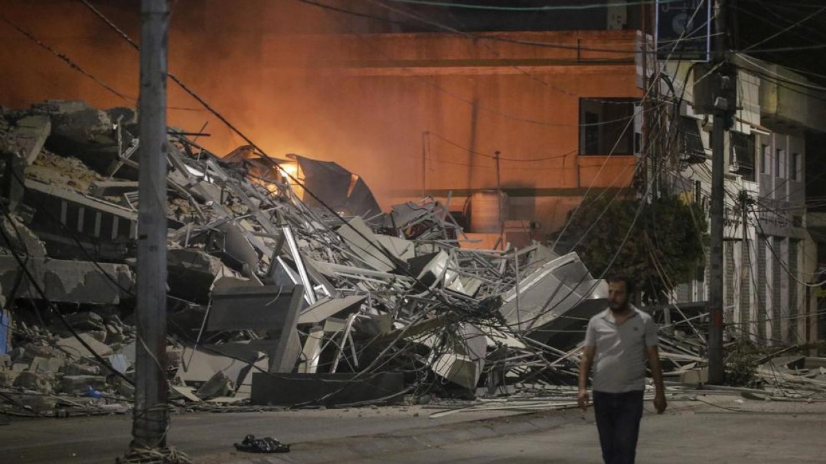 Un palestino pasa junto a las secuelas de un ataque aéreo israelí en la ciudad de Gaza.