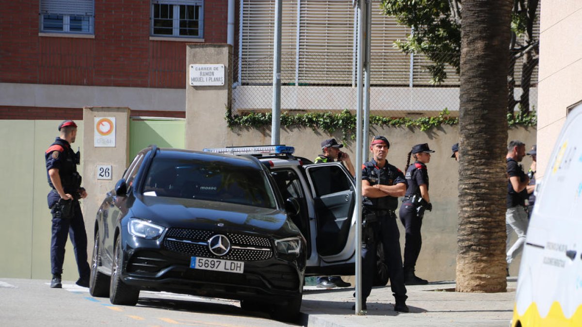 Agentes de los Mossos vigilando la puerta del edificio donde se encuentra atrincherado un hombre, en el barrio de Sarrià de Barcelona.