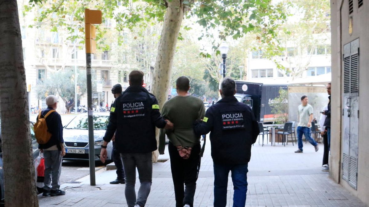 Los Mossos d'Esquadra se llevan a un detenido de uno de los registros en Barcelona en una operación contra una organización criminal italiana afincada en Catalunya vinculada al tráfico de drogas.