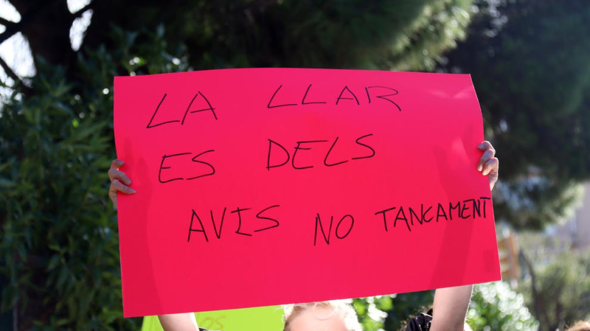 Una dona subjectant una pancarta durant la concentració celebrada a les portes de la Residència de Gent Gran de Reus.