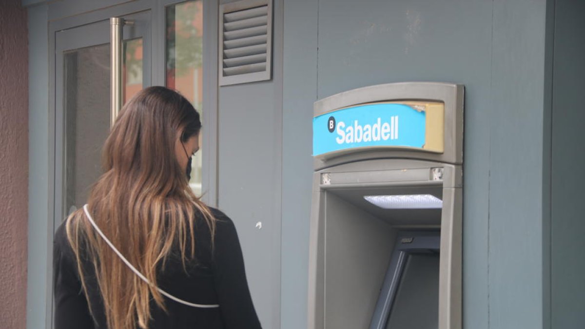 Una clienta del Banc Sabadell retirando efectivo de un cajero.