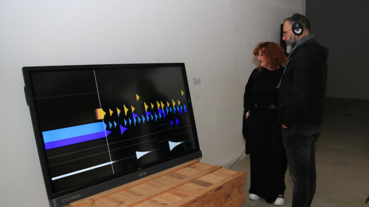 Dos espectadores escoltan la obra 'Contorns', en el marco de la exposición 'FORMS - música visual generativa' en Lo Pati -  Centre d'Art de les Terres de l'Ebre.