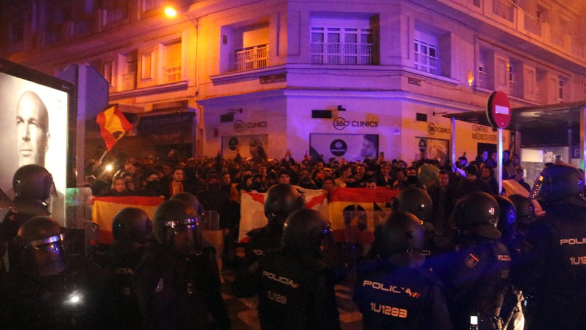 Manifestants espanyolistes s'encaren a policies nacionals antiavalots darrere de banderes espanyoles.