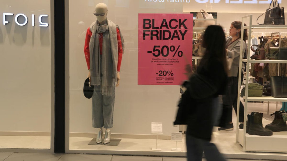 Una chica pasea por delante un escaparate del Parque Central de Tarragona en el que se anuncian descuentos con motivo del Black Friday.