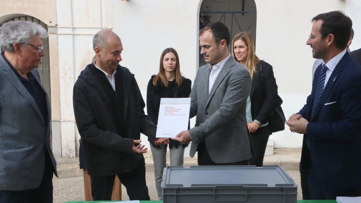 El director general de Memòria Democràtica, Alfons Aragoneses, entrega la memòria d'identificació de Narcís Mediavilla Cardó als seus néts, davant la capsa que conté les restes del soldat barceloní.