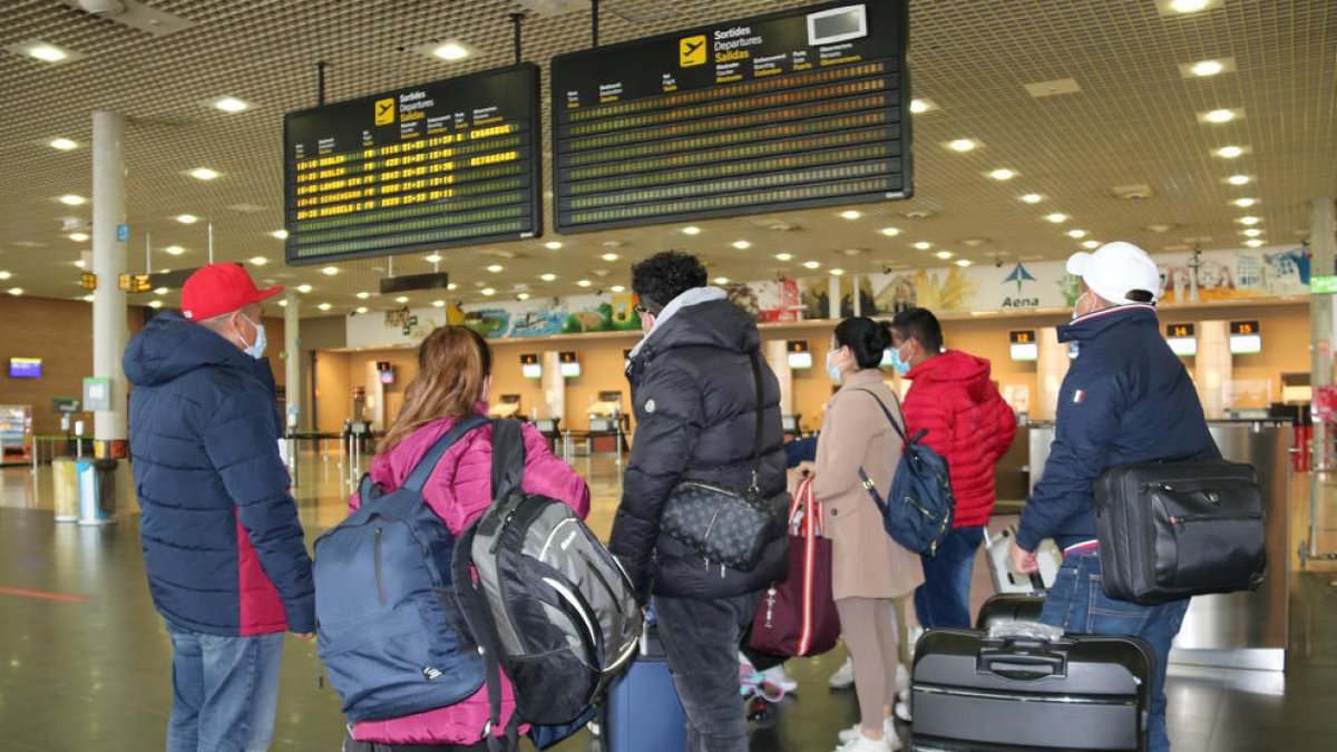 Un grup de passatgers miren el tauler de sortides de l'aeroport de Reus.