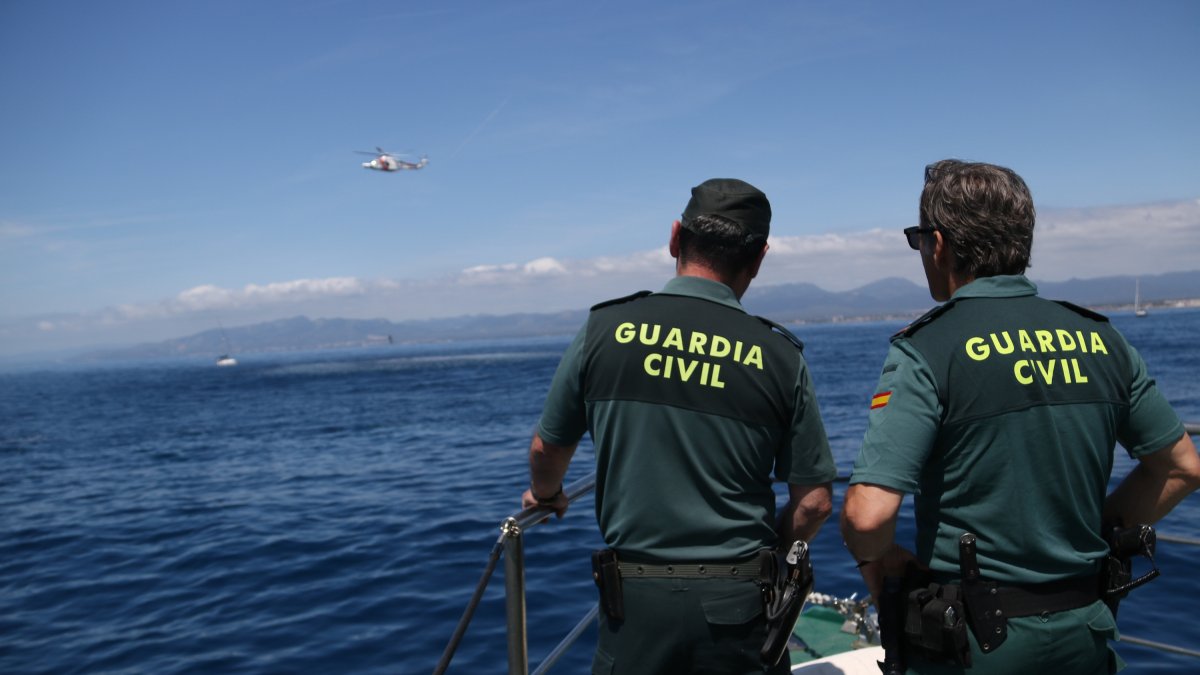 Dos agents de la Guàrdia Civil observen com l'helicòpter de Salvament Marítim maniobra en un simulacre a la costa de Cambrils.