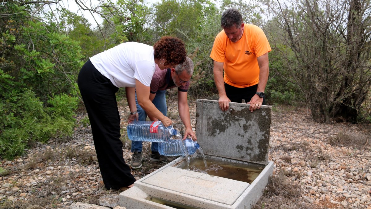 Anna Sanitjas, directora general de Boscos i Gestió del Medi d'Acció Climàtica, i el director ebrenc Jesús Gómez, omplen un dels abeuradors amb el president de la societat de caçadors de Santa Bàrbara